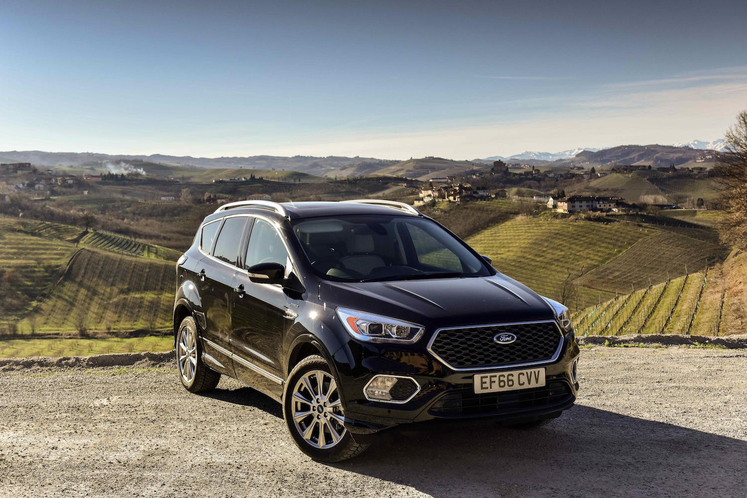 Black Ford Kuga parked facing three-quarters overlooking countryside.
